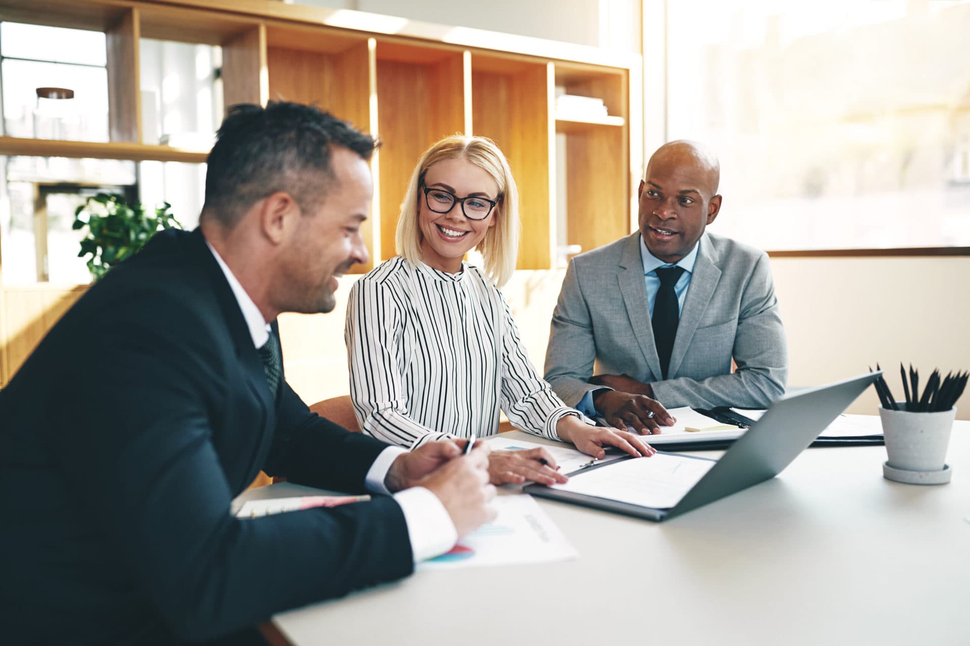 Three smiling businesspeople discussing paperwork together